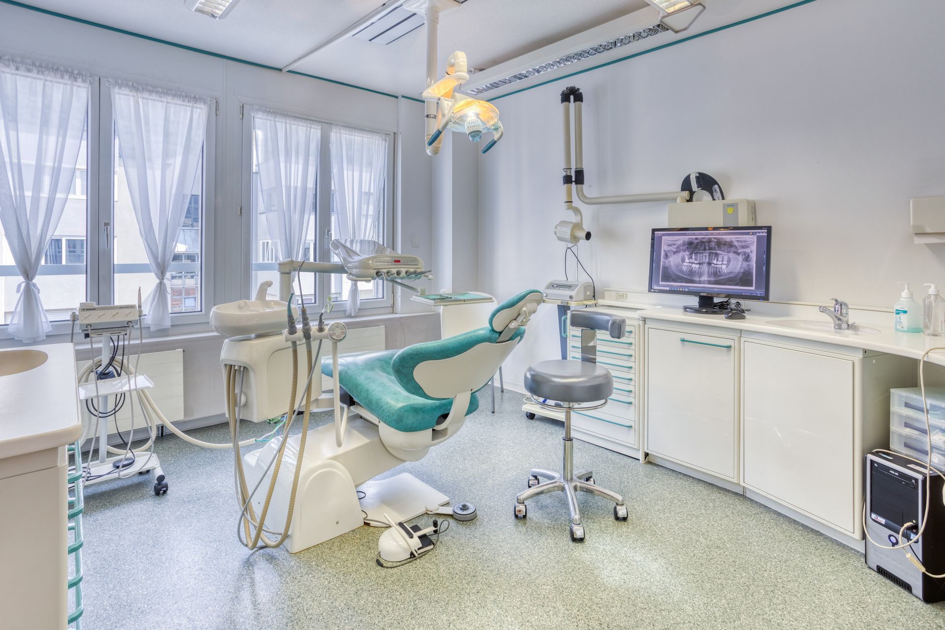 Un cabinet dentaire avec un fauteuil dentaire et un ordinateur.