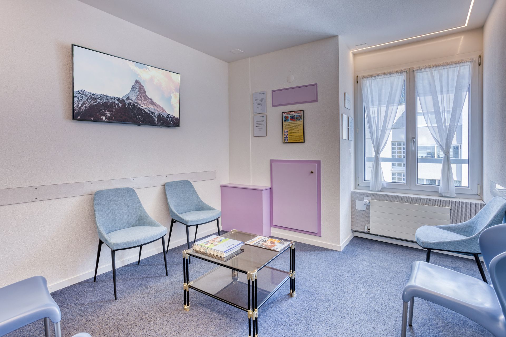 Une salle d'attente avec des chaises, une table basse et un tableau au mur.