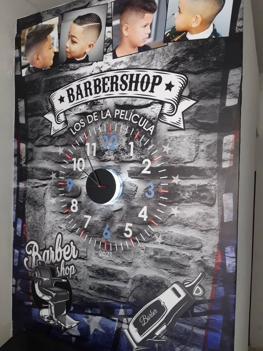 Un mural de barbería con un reloj, fotos de cortes de pelo y el texto