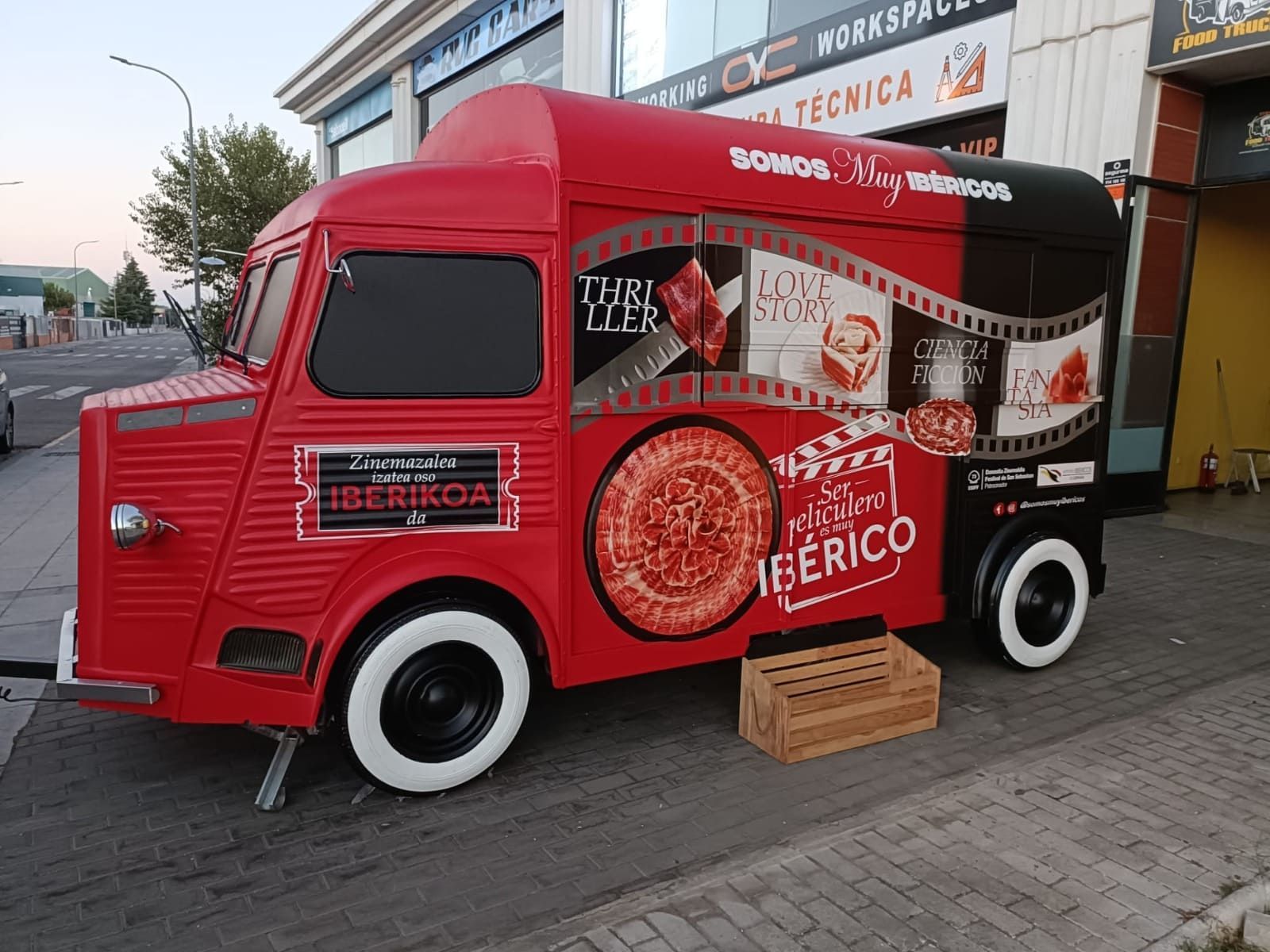 Un camión de comida rojo y negro estacionado en una acera, con la marca