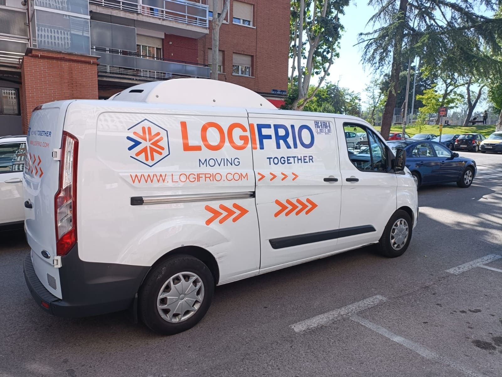 Una furgoneta frigorífica blanca de la marca Logifrio aparcada en un estacionamiento al aire libre en un día soleado.