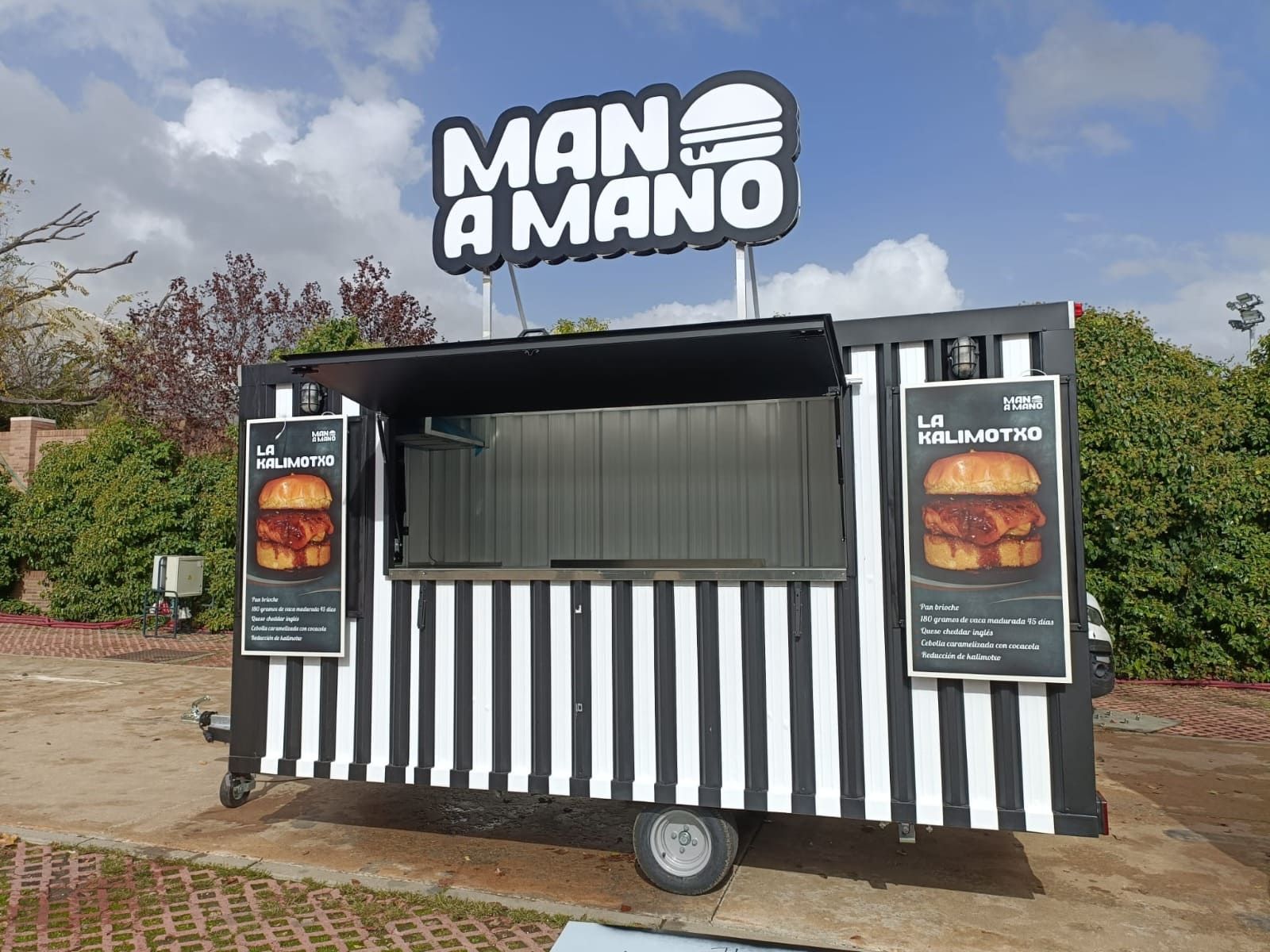 Un camión de comida a rayas blancas y negras, especializado en hamburguesas