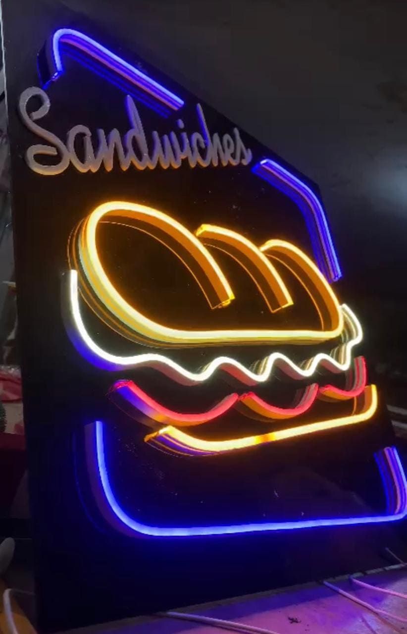 Un letrero de neón sobre fondo negro muestra la palabra "Sándwiches" encima de un gráfico iluminado de un sándwich.