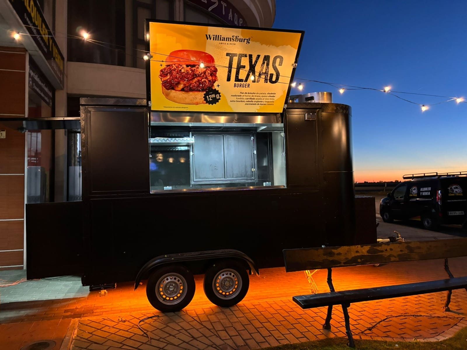 Un remolque de comida negro con un letrero amarillo de hamburguesa