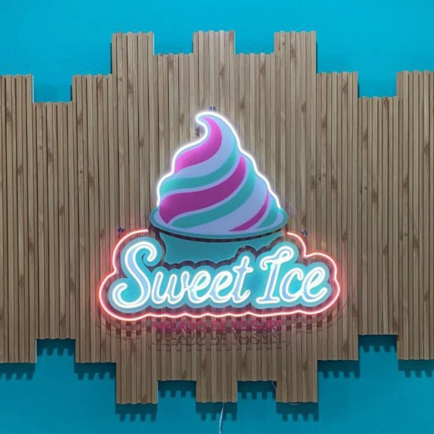 Un letrero de neón con la inscripción "Sweet Ice" en azul claro con un contorno rosa, coronado con un remolino de hielo de neón morado, rosa y turquesa.