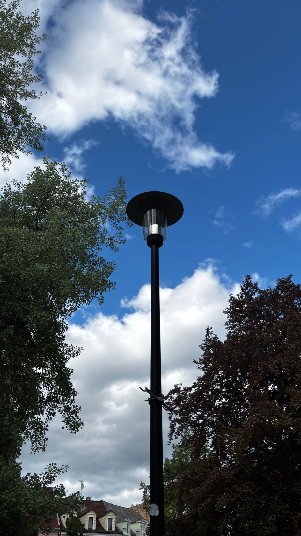Les lampadaires au crépuscule, de longs poteaux avec des lampes doubles, brillent contre un ciel bleu.