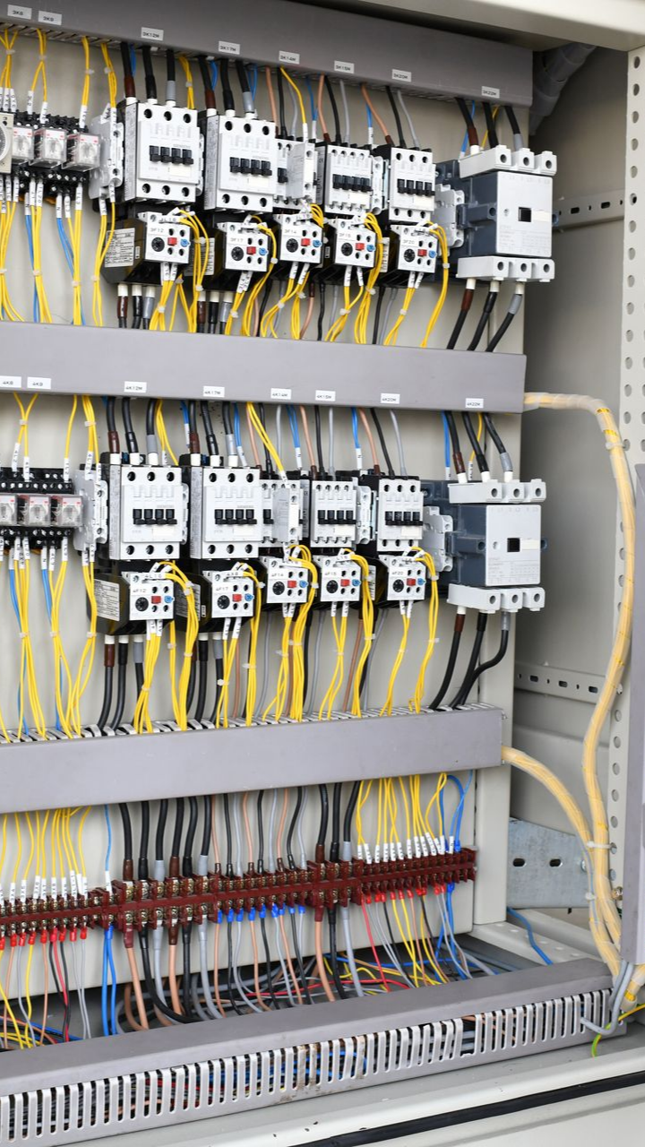 Panneau de commande électrique avec fils jaunes et noirs connectés aux interrupteurs et aux bornes.