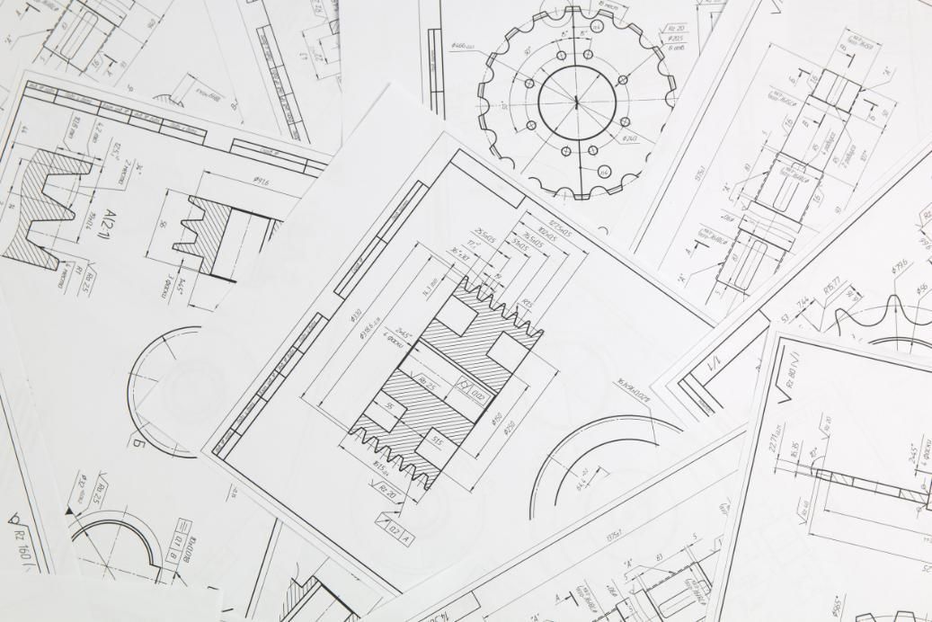 Planos esparcidos sobre una superficie blanca, que presentan diseños arquitectónicos y dibujos técnicos.