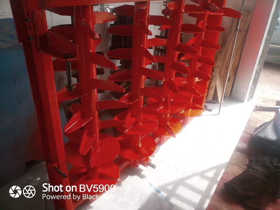 Implemento agrícola de metal rojo con múltiples cuchillas en ángulo.