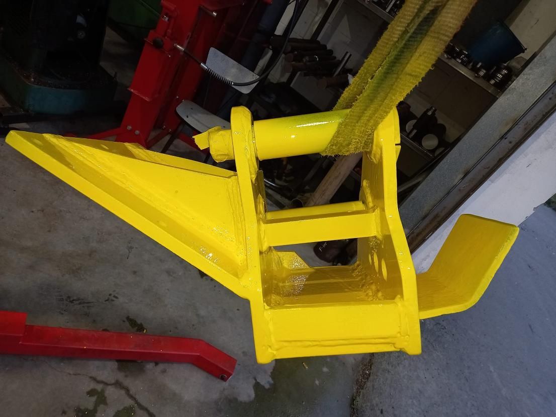 Accesorio de metal de color amarillo, posiblemente para un vehículo, que se levanta mediante una correa verde.