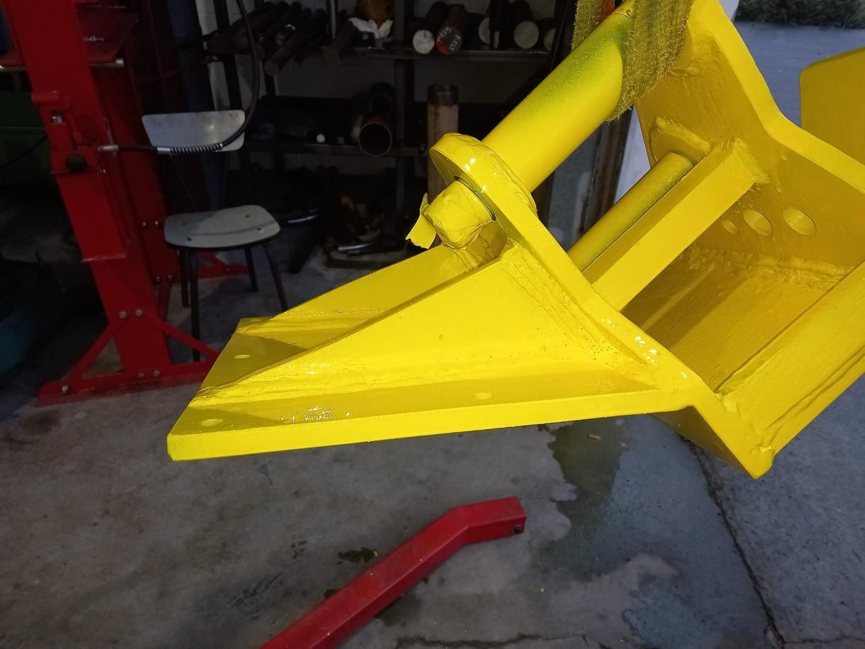 Estructura metálica pintada de amarillo, posiblemente parte de maquinaria, con un cilindro hidráulico acoplado.