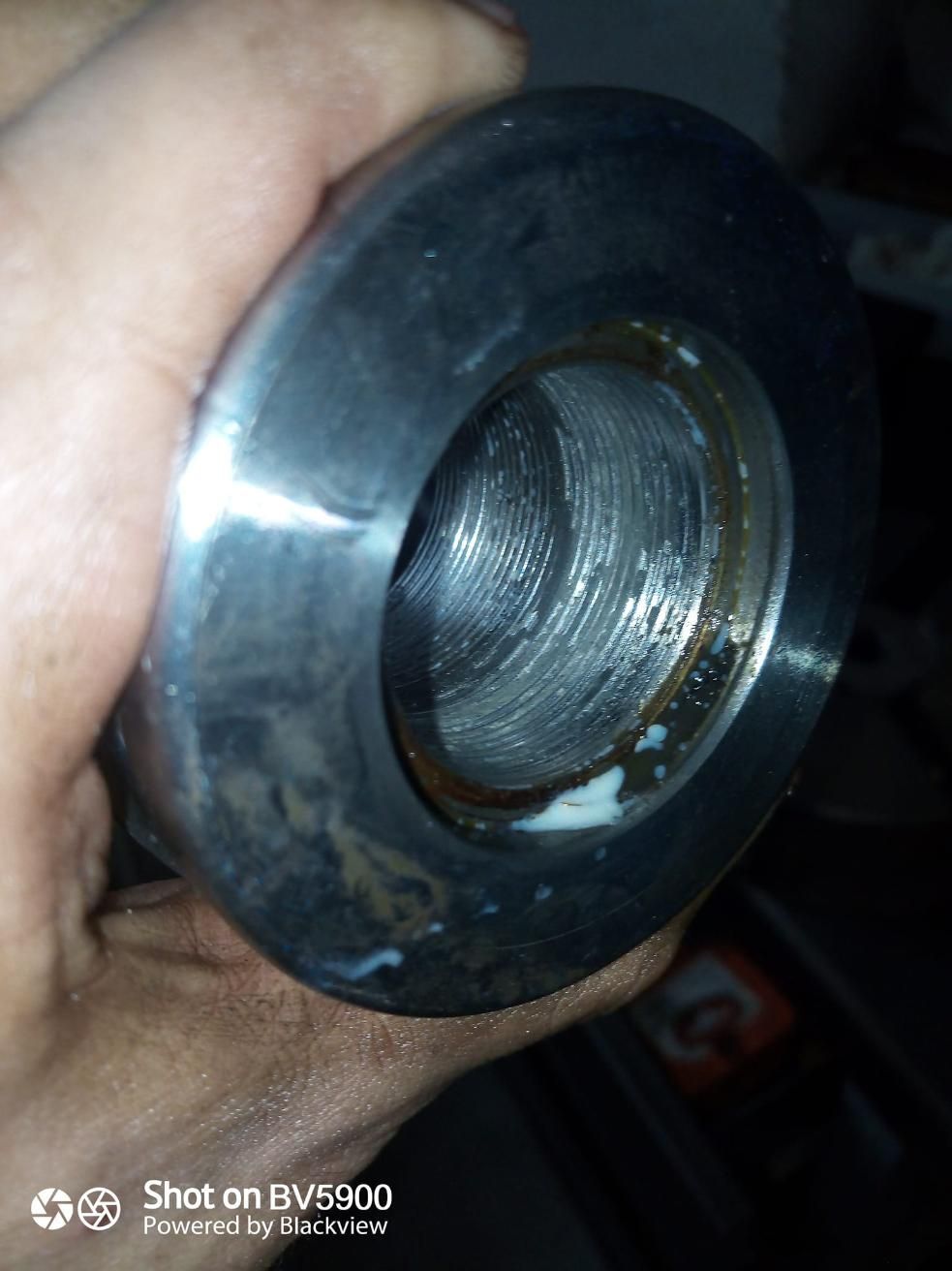 Primer plano de un cilindro metálico con un orificio roscado. Una mano lo sostiene.