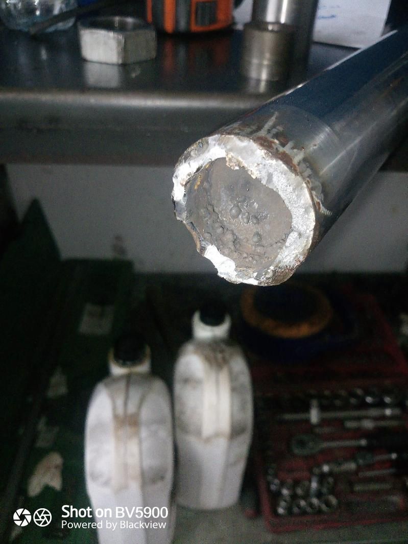 Tubo metálico roto, vista de cerca. Rotura irregular, posiblemente debida a la tensión. En un taller.