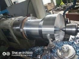 Un cilindro de metal que se mecaniza en un torno en un taller, generando virutas de metal.