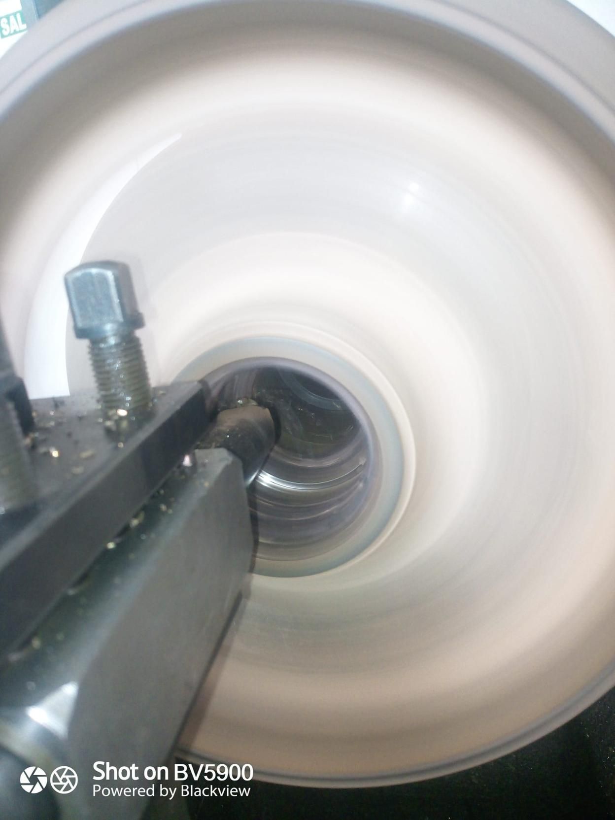 Un torno que corta el interior de un cilindro de metal, creando un efecto brillante y borroso a partir de la rotación.