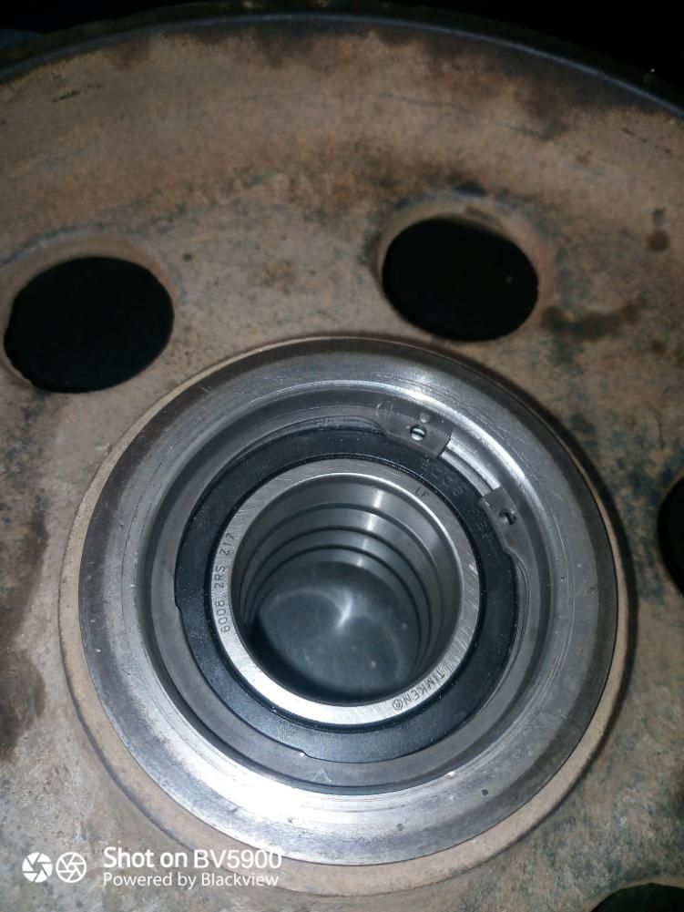 Vista de cerca de una pieza metálica de un automóvil con un cojinete central y un anillo de retención.