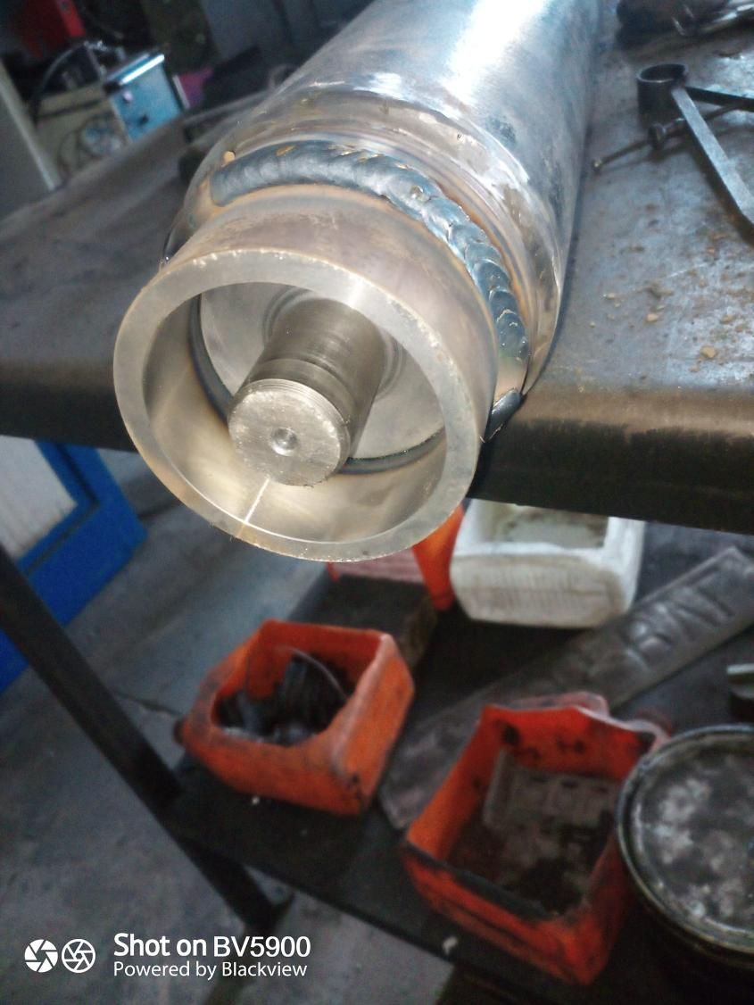 Componente cilíndrico metálico con extremo circular y soldadura visible.