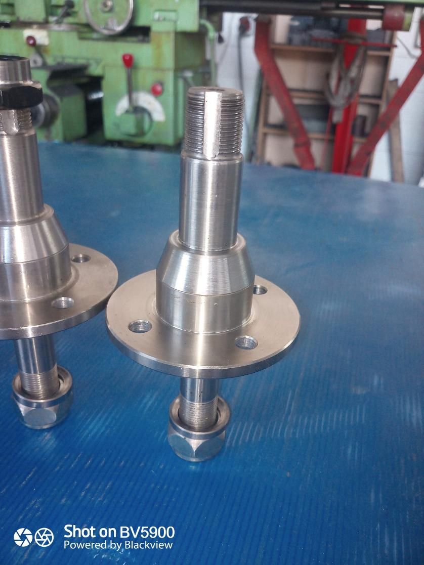 Dos husillos metálicos brillantes con bridas de montaje circulares y tapas roscadas, colocados sobre una superficie azul.