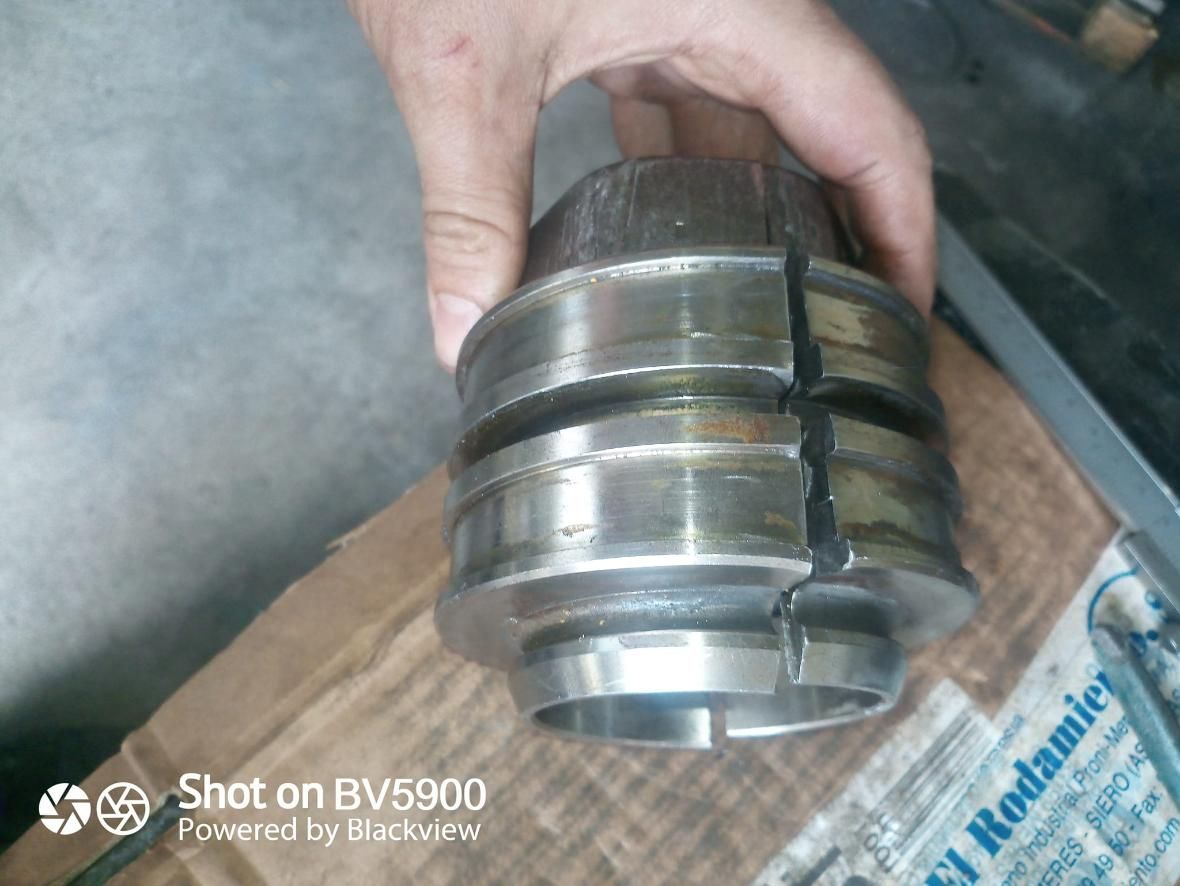 Una persona sostiene un componente metálico partido. El componente es de plata y tiene secciones circulares.