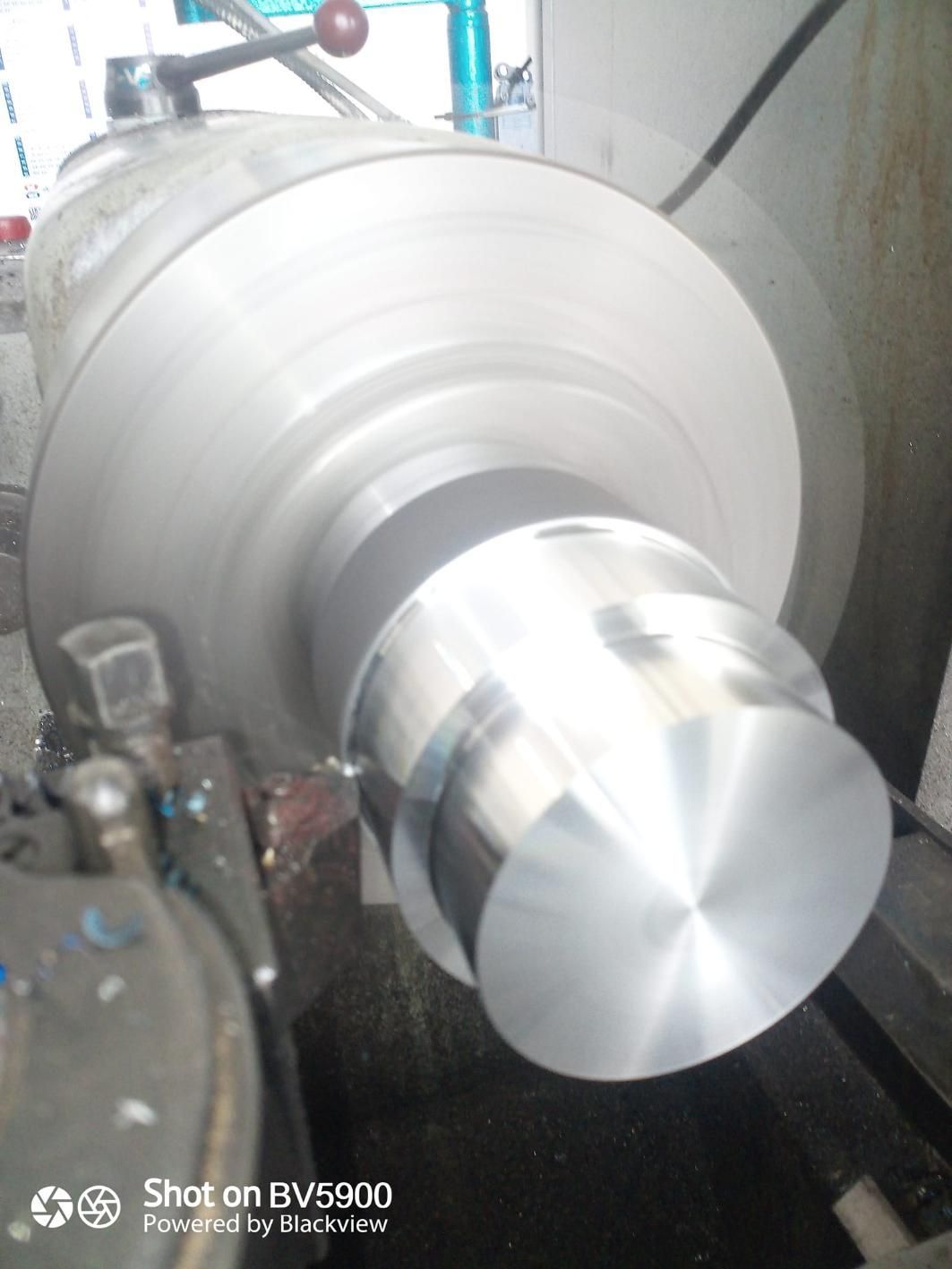 Un cilindro de metal que se mecaniza en un torno; la herramienta giratoria está dando forma al metal.