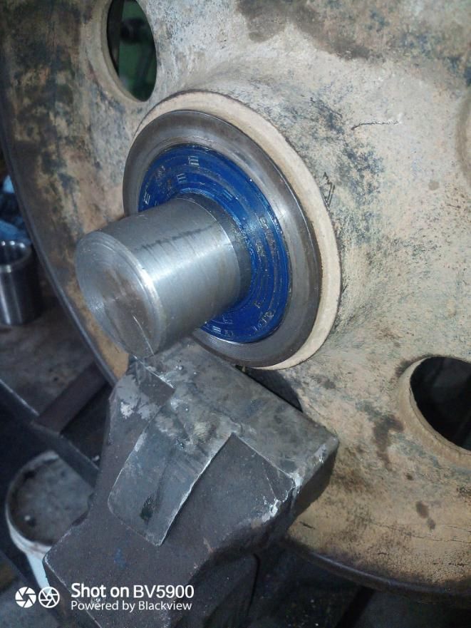 Un cojinete engrasado de color azul sobre un eje de metal dentro de una rueda grande, circular y de color gris