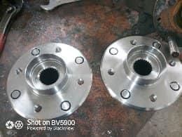 Dos brillantes cubos de rueda de automóvil de metal con orificios para tornillos se encuentran en un banco de trabajo