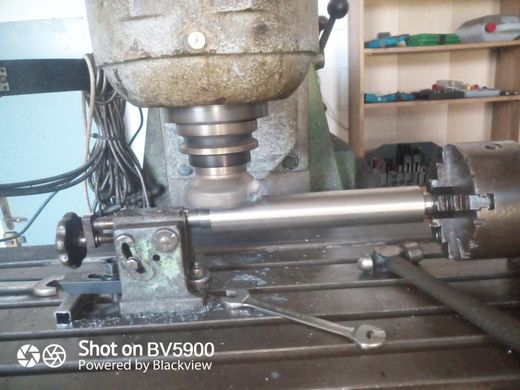 Una fresadora corta un cilindro metálico. El cilindro está sujeto por dos abrazaderas. Se ven chispas.