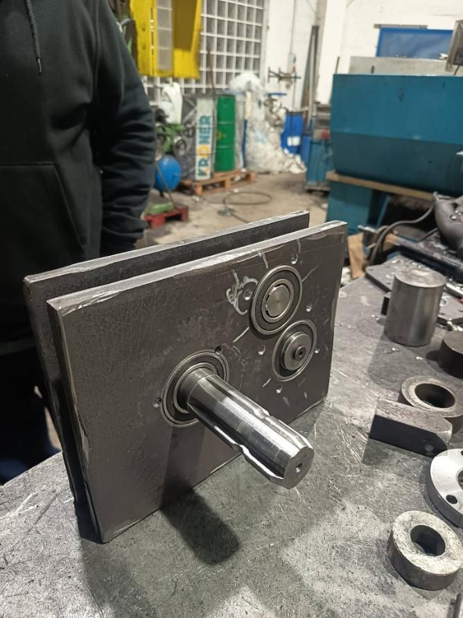 Proyecto de fabricación de metal: un eje con dos placas, soportes de cojinetes, en un banco de trabajo.