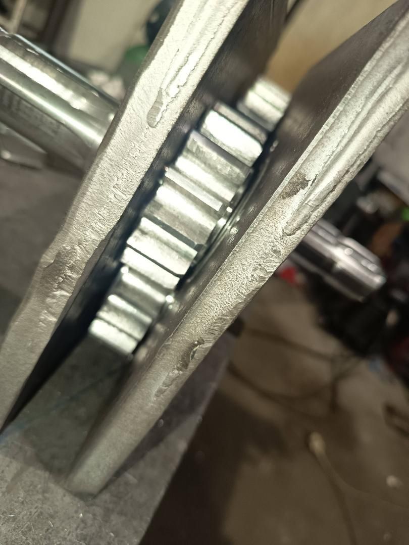 Vista de cerca de engranajes que engranan entre dos placas de metal, probablemente parte de una máquina o motor.