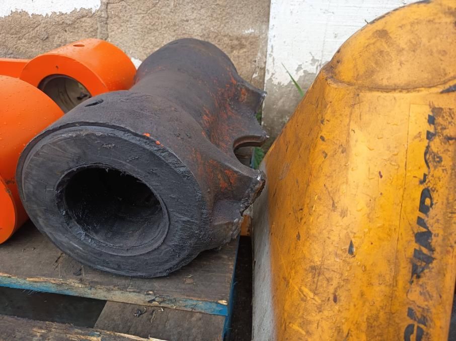 Piezas de maquinaria industrial de color negro y naranja descansan sobre una paleta de madera.