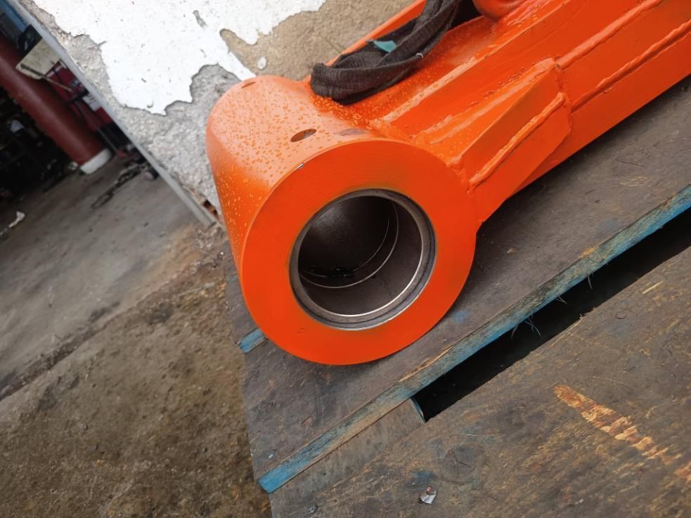 Primer plano de un componente industrial naranja con un gran orificio cilíndrico y revestimiento metálico.