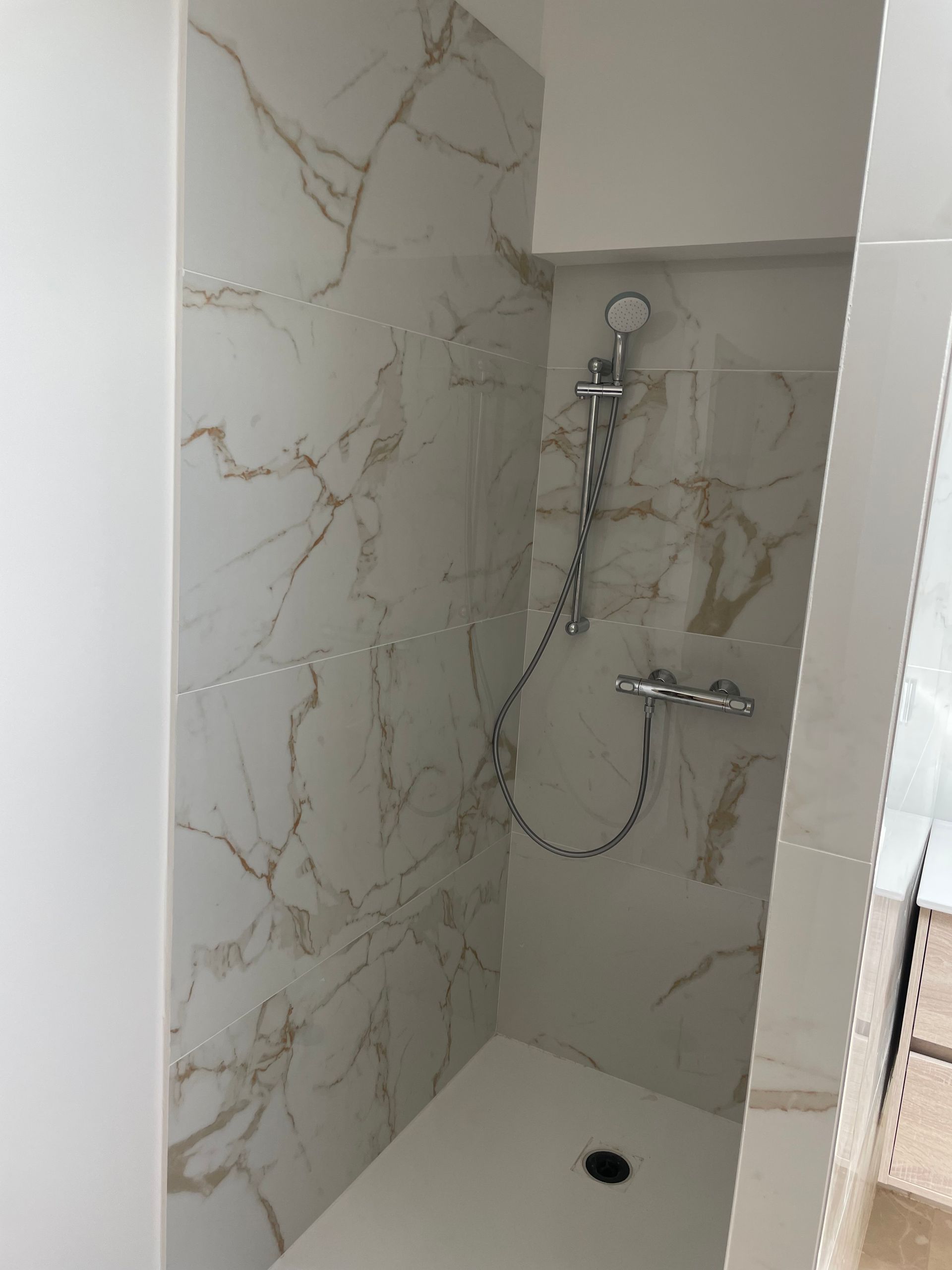 Pose de carrelage imitation marbre blanc veine or pour une douche italienne