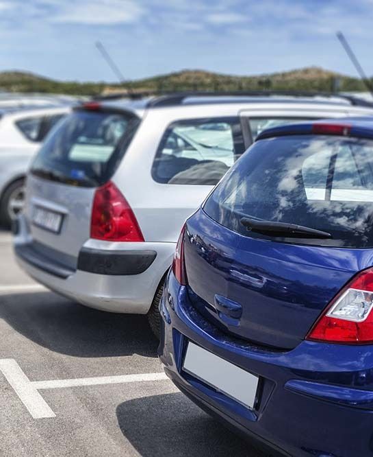 Un coche azul está aparcado al lado de un coche blanco en un estacionamiento.