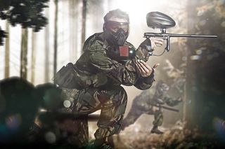 Mies värikuulapelivarusteissa