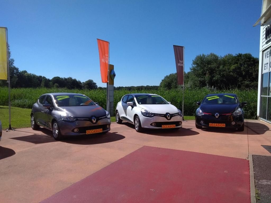 Trois voitures compactes garées à l'extérieur sur un terrain ensoleillé.