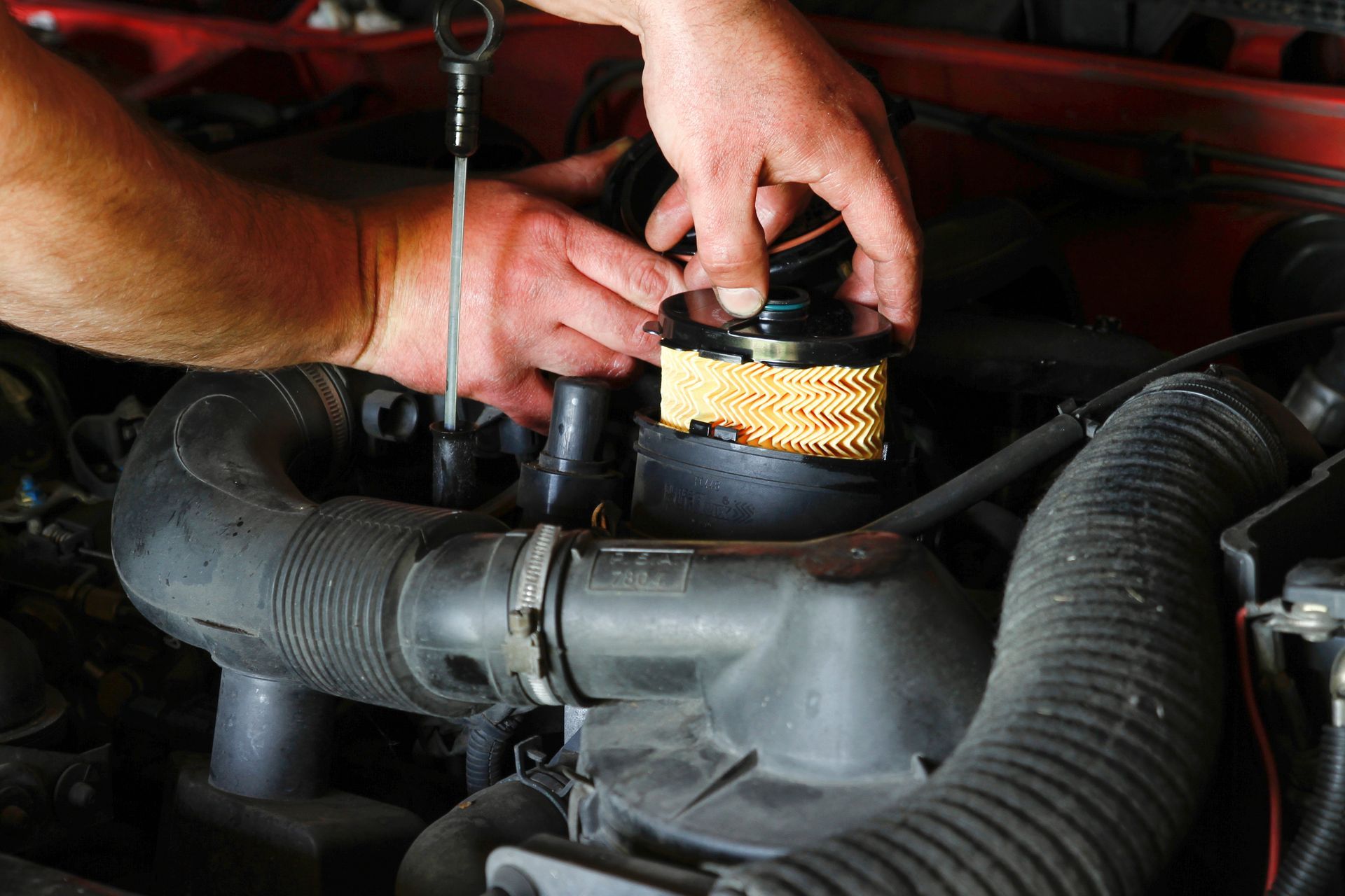 Mains remplaçant un filtre à air dans le compartiment moteur d'une voiture.