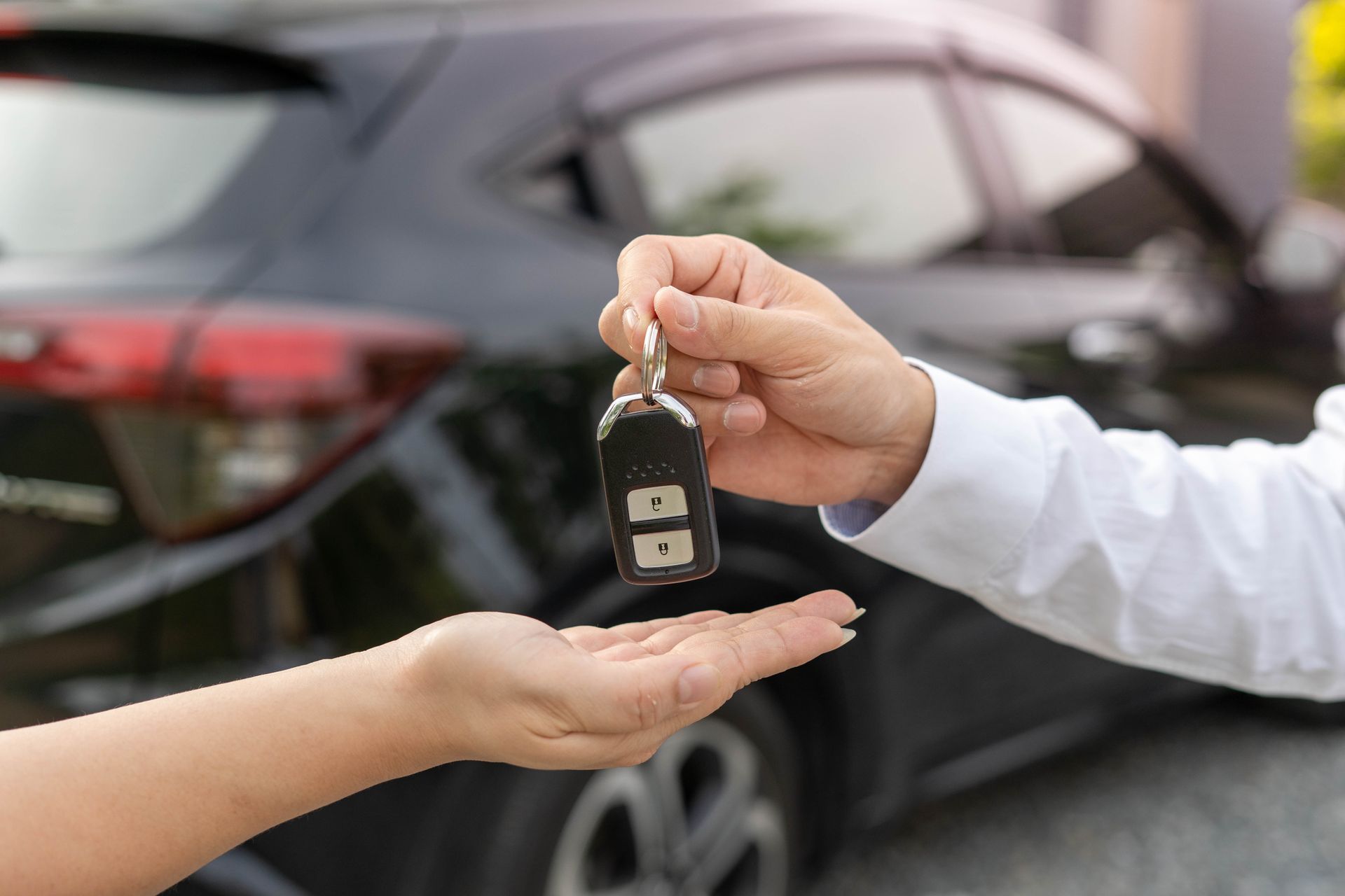 Remise de clés de voiture devant une voiture noire.
