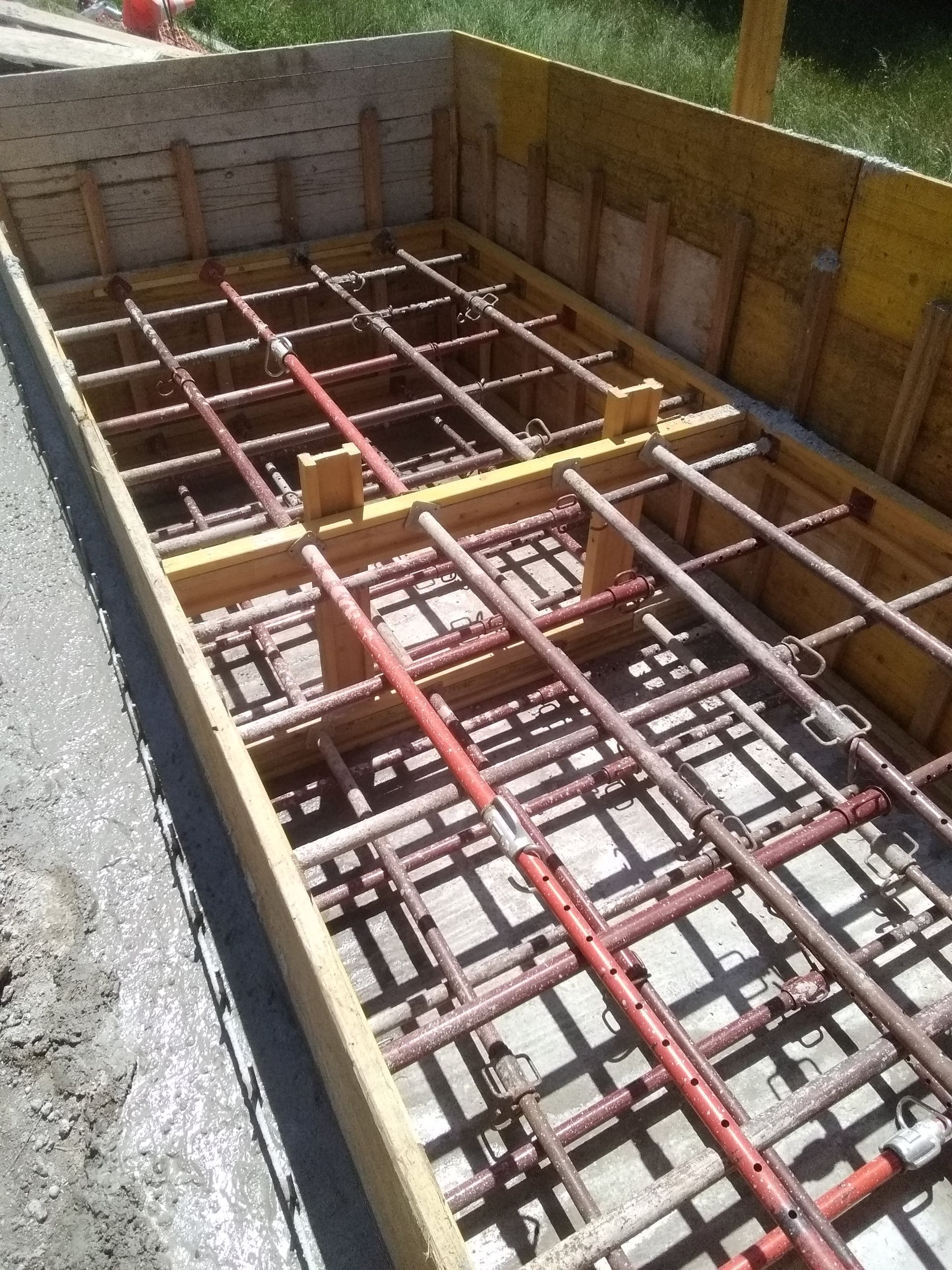 Tranchée de fondation avec treillis d'armature rouge et coffrage en bois pour la construction d'une dalle en béton