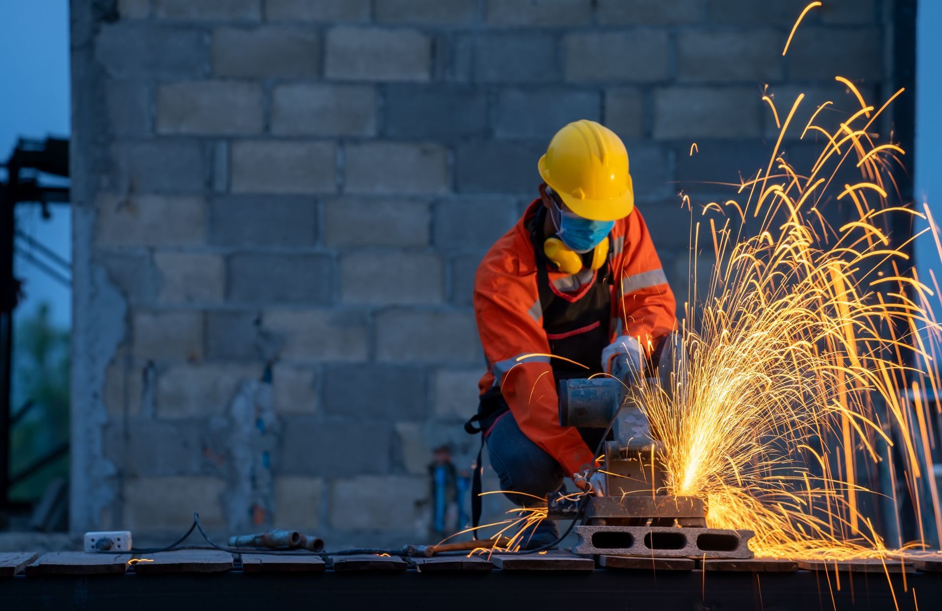 Un trabajador de la construcción está cortando un trozo de metal con una amoladora.