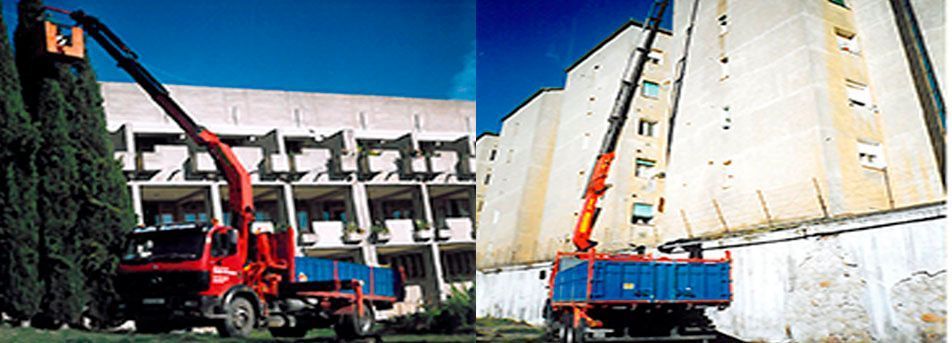 Grúas de construcción levantan una estructura de hormigón derrumbada en un sitio de demolición, con camiones rojos y azules cerca.