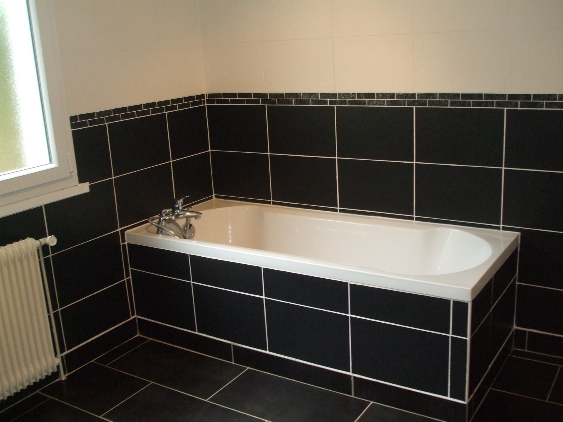 Salle de bains avec baignoire blanche et carrelage noir