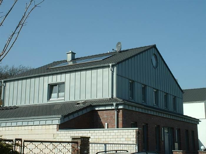 Ein Haus mit einem grauen Dach und einem runden Fenster