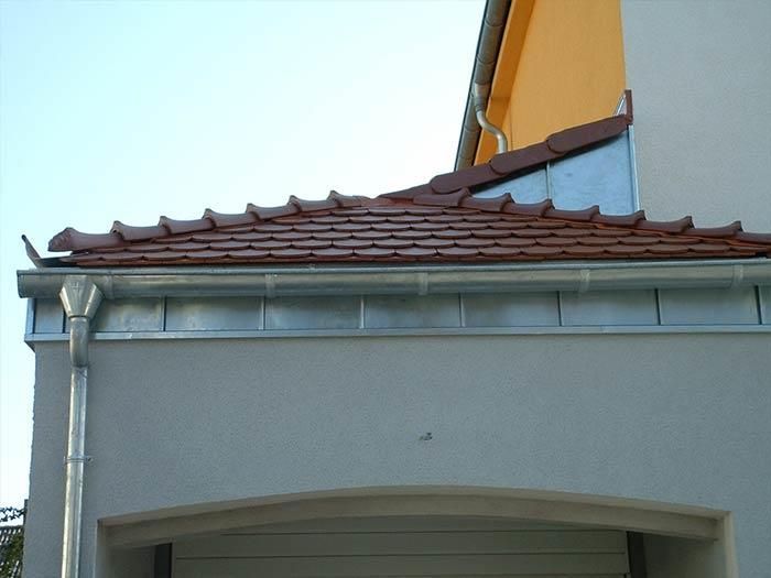Ein Haus mit einem roten Ziegeldach und Dachrinnen