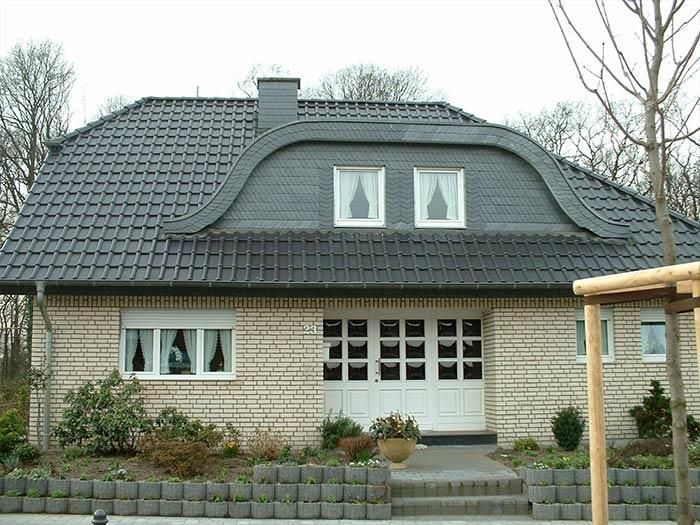 Ein Backsteinhaus mit einem schwarzen Dach und zwei Fenstern
