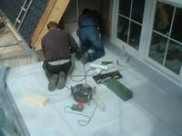 Eine Gruppe Männer kniet auf dem Boden und arbeitet auf einem Dach.