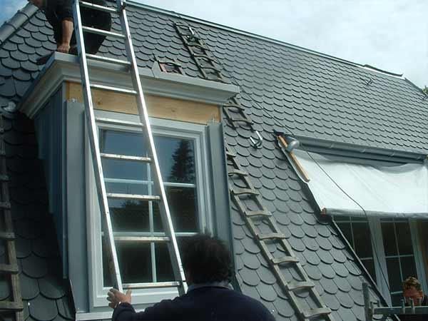 Ein Mann auf einer Leiter arbeitet auf einem Dach