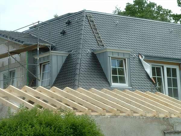 Das Dach eines Hauses wird aus Holzbalken gebaut.