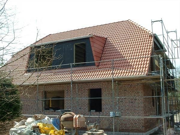 Ein Backsteinhaus mit rotem Ziegeldach wird gebaut