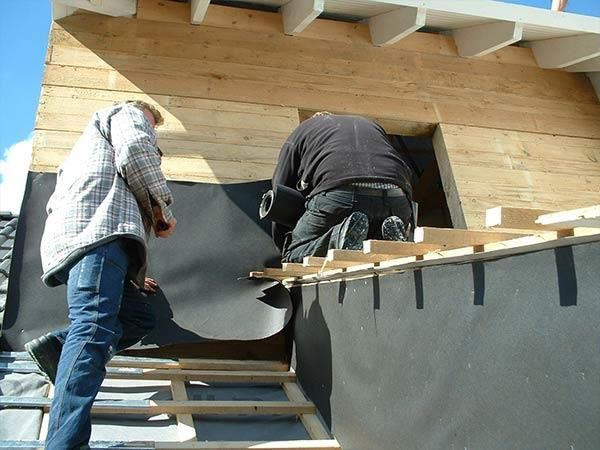 Zwei Männer arbeiten an einem Holzgebäude