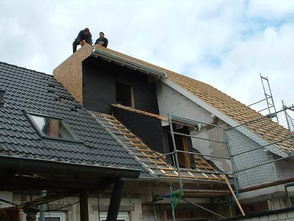 Zwei Männer arbeiten auf dem Dach eines Hauses